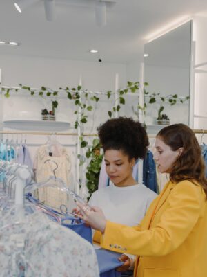 Two women shopping for clothes in a modern boutique, guided by a personal stylist.